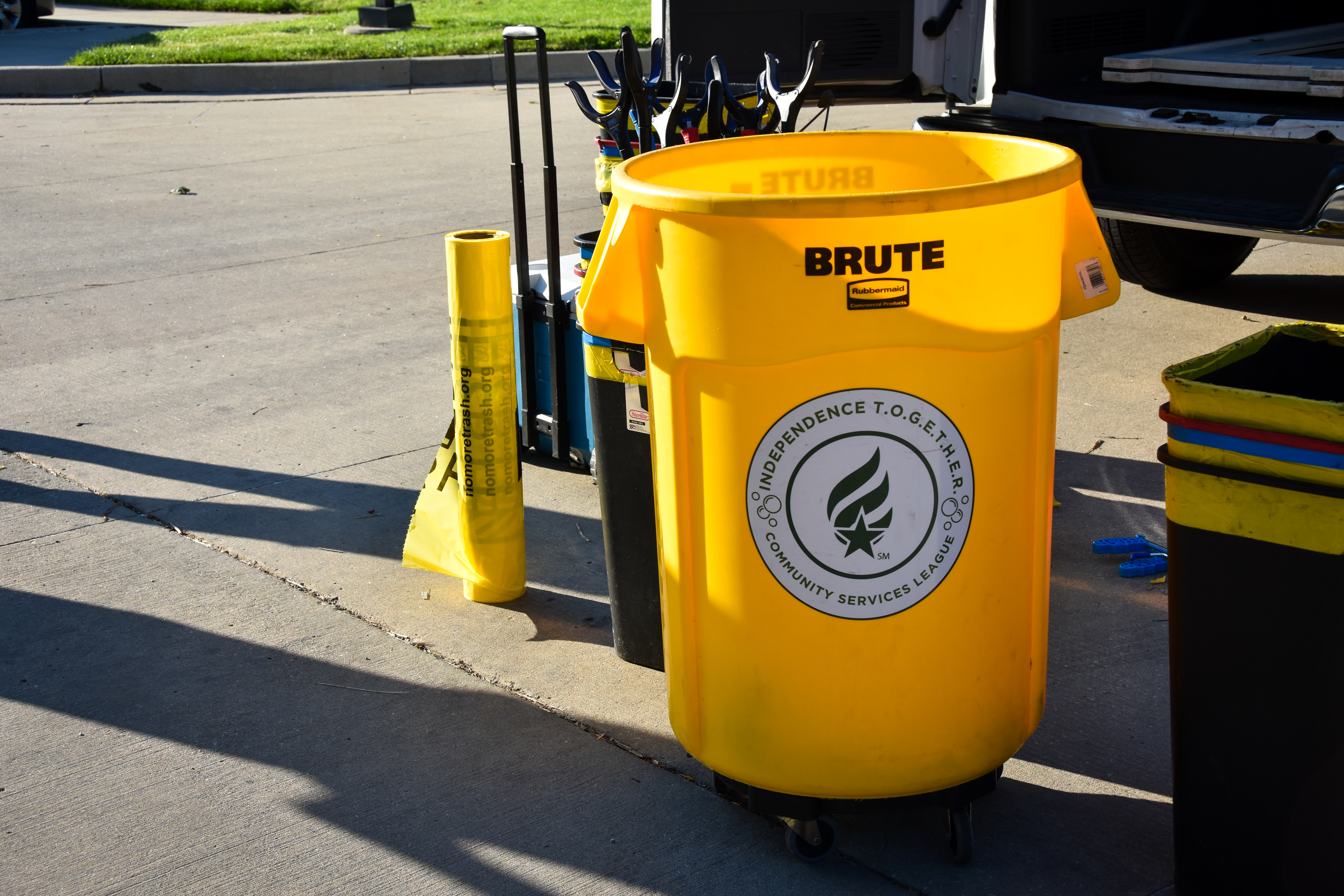 A bright yellow trash can with a green and white sticker on the front that reads Independence TOGETHER 