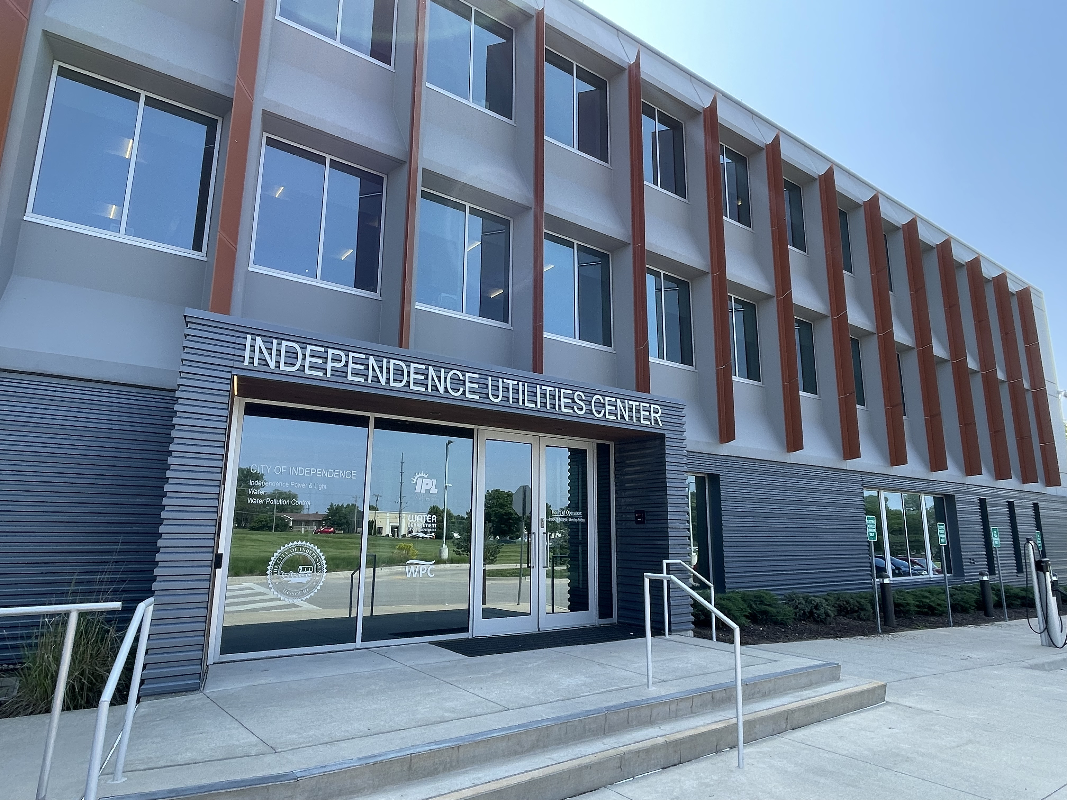 The outside of the Independence Utilities Center on a bright sunny day. The sun is reflecting off the glass doors