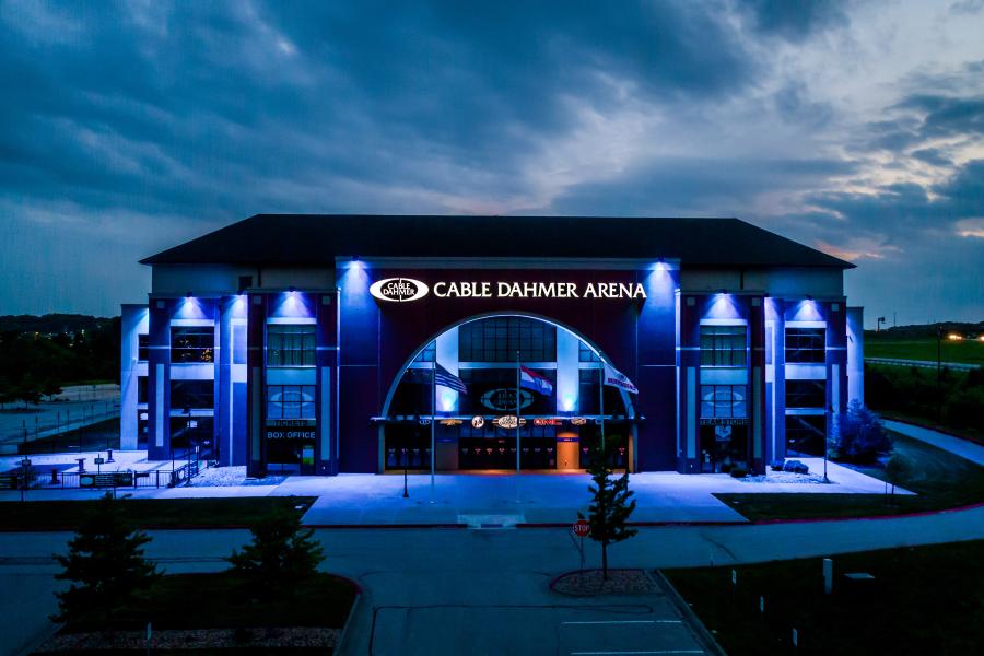 An image of a blue lit up Cable Dahmer Arena exterior view on a cloudy evening.