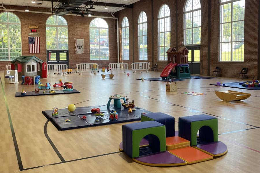 An image of toddler town toys and playground equipment set up in the Sermon Center gymnasium on a cloudy morning.