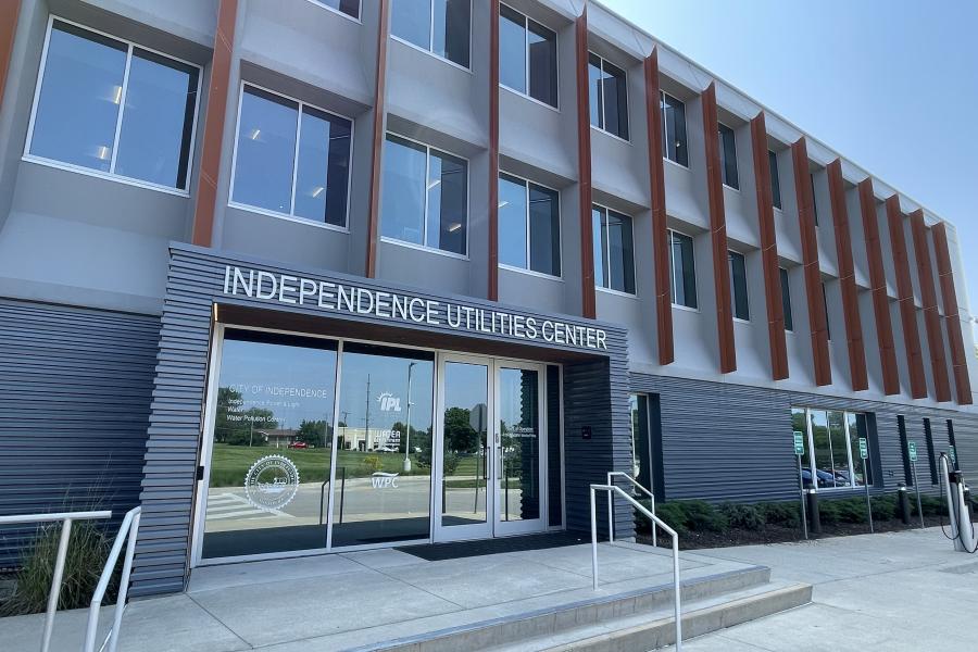 The outside of the Independence Utilities Center on a bright sunny day. The sun is reflecting off the glass doors