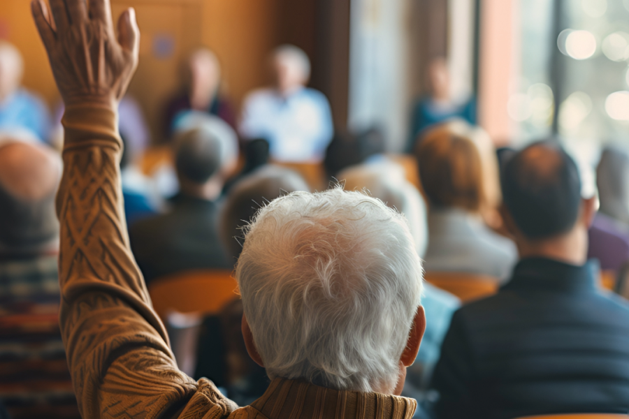 Image of a person raising their hand during a town hall meeting
