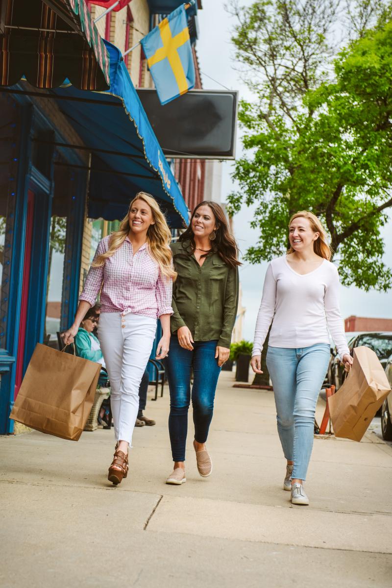 Image of women walking down sidewalk with shopping bags