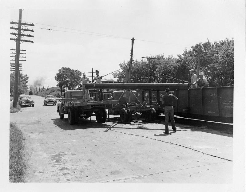 1950s era - men unloading pipeline from truck