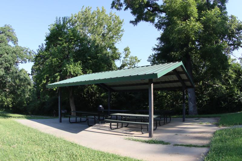An image of the Fairmount Park shelter with four picnic tables and trees in the background.