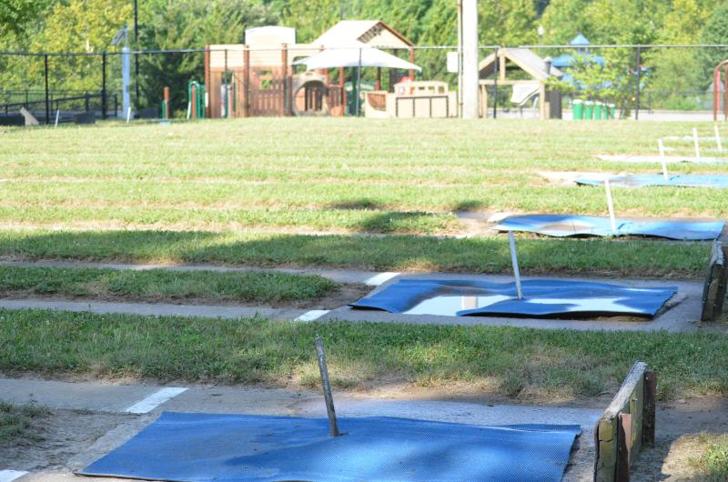 A close up image of the horseshoe pits inside a fenced area at McCoy Park with one of the playgrounds in the background.
