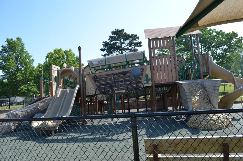 An image of one of the playgrounds at McCoy Park featuring a wagon and an old west theme surrounded by a fence.