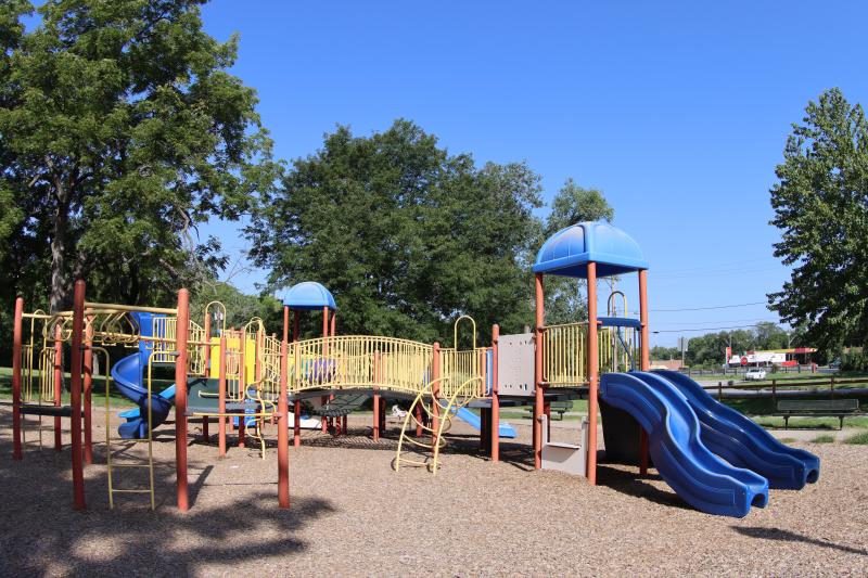 An image of a blue, red and yellow playground at Rotary Park on a sunny day.
