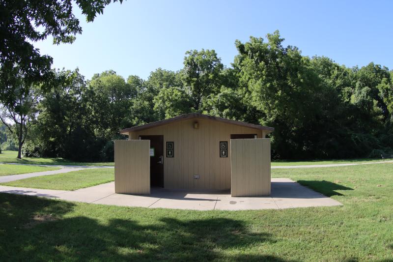 An image of a men's and women's restroom structure near some trees at Rotary Park.