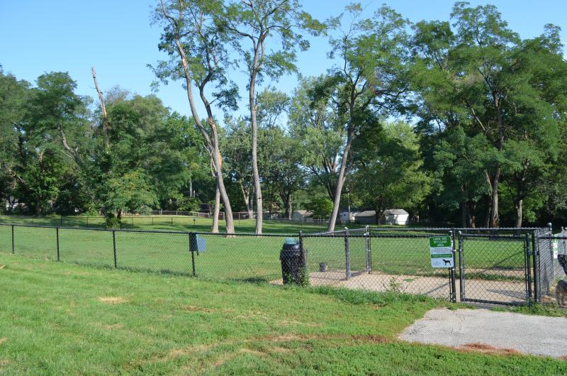 An image of the gate entrance to the fenced in dog park at Santa Fe Park with trees in the background.