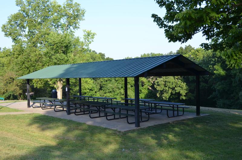 An image of the Van Hook Park pavilion with picnic tables shaded by trees.