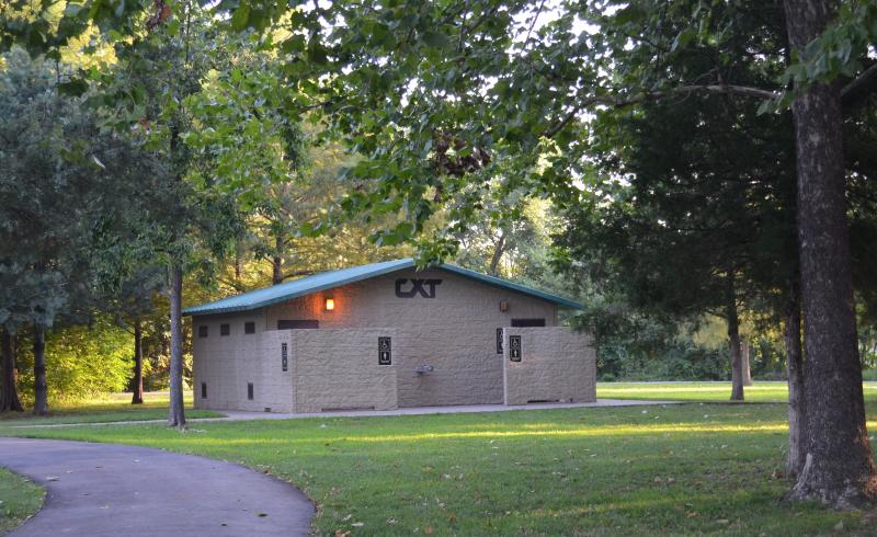 A distant image of the men's and women's restroom structure surrounded by trees at Waterfall Park.