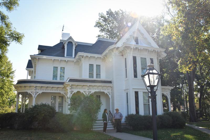 Image of the Truman Home with a park ranger and a tour guest on the front porch. 