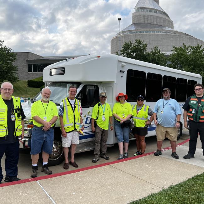 Emergency Management Department volunteers stand before their mobile command bus in front of the Community of Christ spire at the annual Fireworks Celebration.