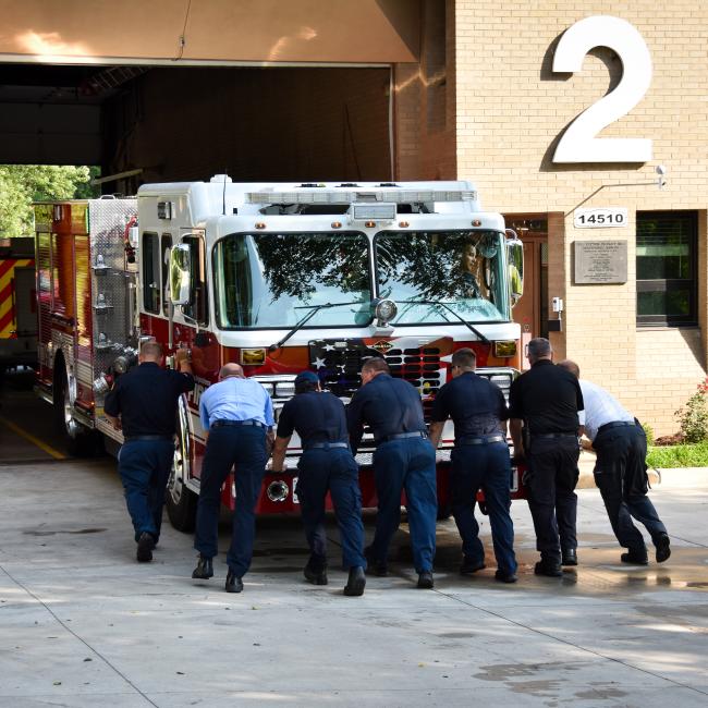 Image of firemen pushing a firetruck into the bay of Fire Station number 2