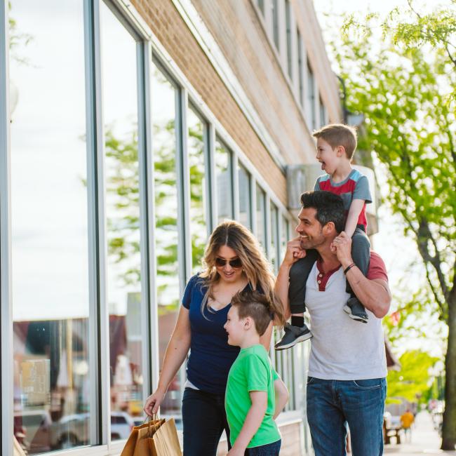 Image of family walking down sidewalk with shopping bags