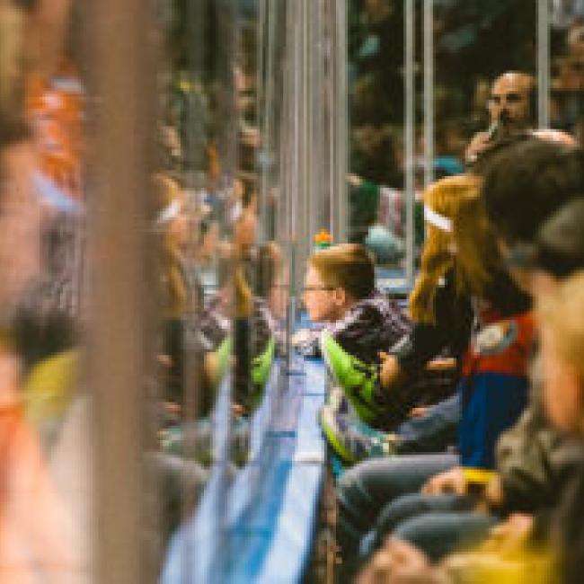 Fans watch a KC Mavericks game through the hockey glass