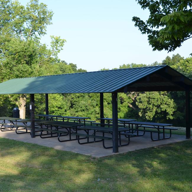 An image of the Van Hook Park pavilion with picnic tables shaded by trees.